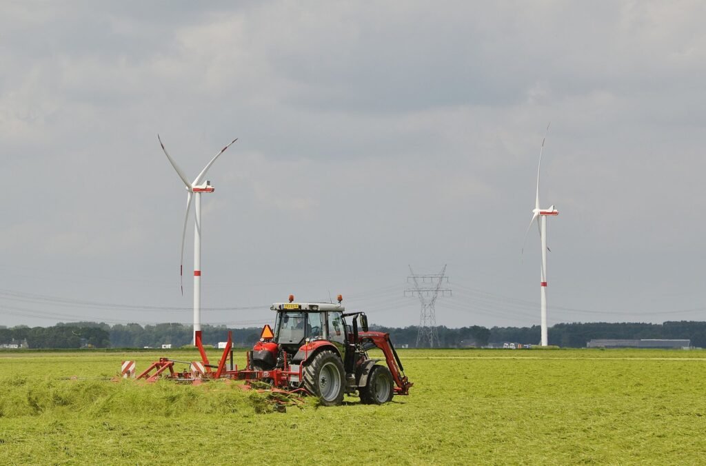 Tracteur avec une faneuse au travail dans une prairie fauchée