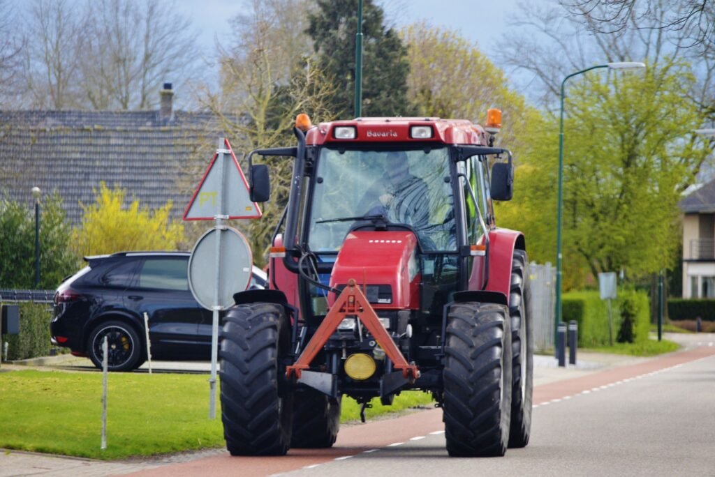 Tracteur rouge circulant sur une route de village